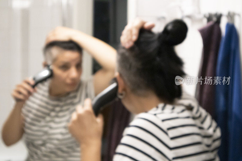 女人一边剪头发一边照镜子