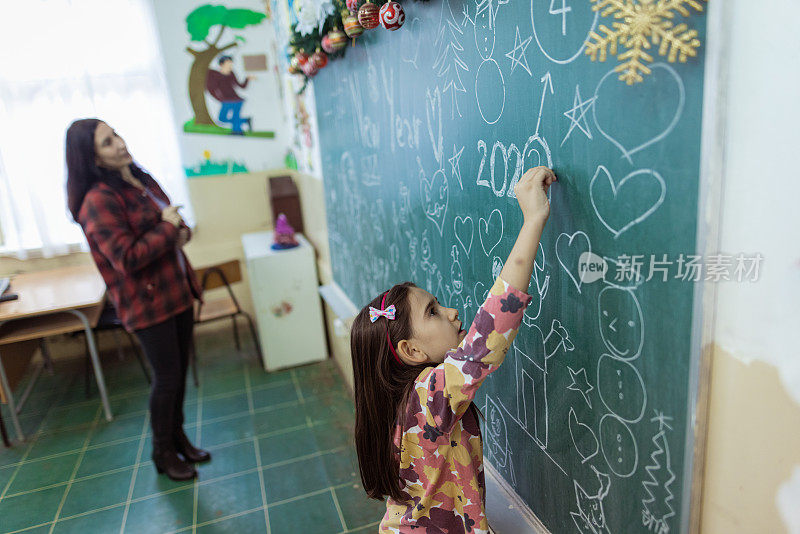 学校老师和学生在学校黑板上画圣诞装饰品