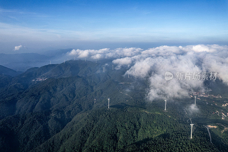 一组风力涡轮机在被雾覆盖的山顶上