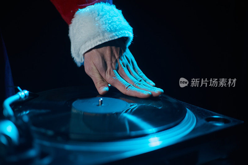 穿着红色圣诞老人服装的嘻哈DJ在唱盘甲板上刮着黑胶唱片