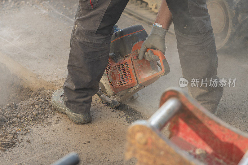 沥青切割工人使用带圆形刀片的电动沥青切割机或锯切割沥青地面，作为修复或解决问题的过程。