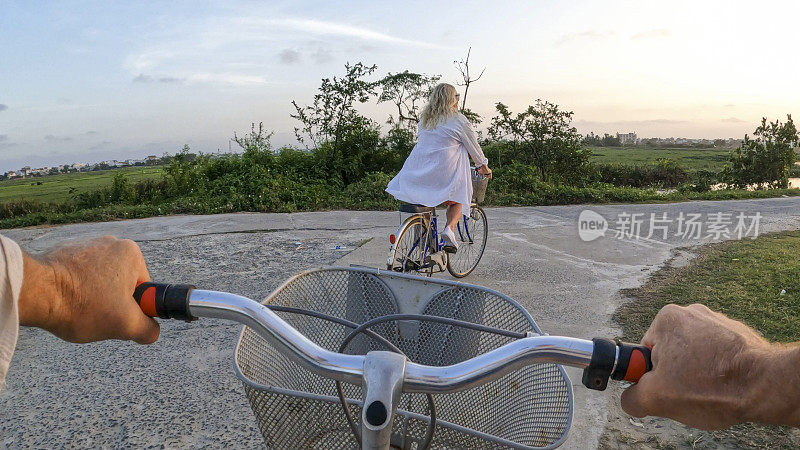 夫妇骑自行车穿过稻田的个人视角