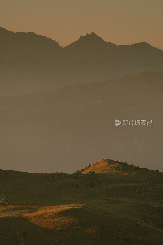 黄昏时橙色天空下青山的宁静景色。远处雾蒙蒙的群山。特伦蒂诺完美的度假胜地