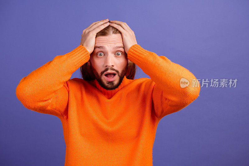 照片中，穿着橙色毛衣的男子双手摸着头，当意识到他需要多少钱时，他感到困惑和震惊，这张照片被隔离在紫色的背景上
