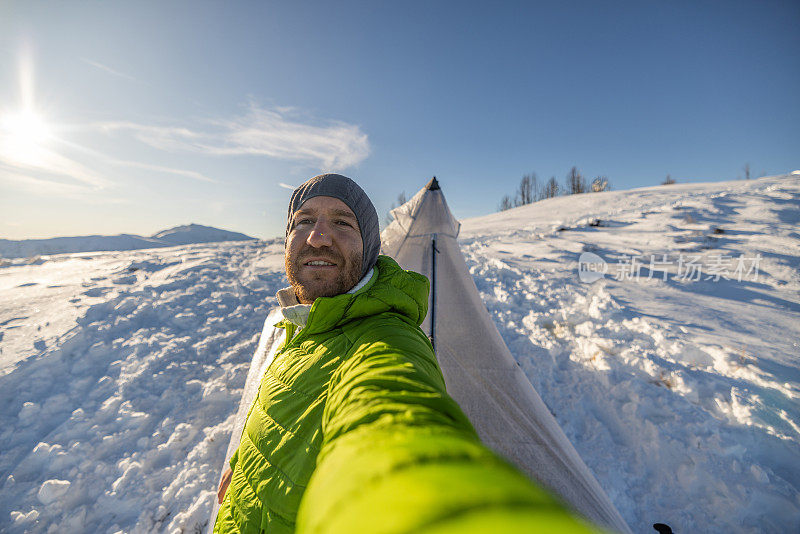 一名男子在雪地里野外露营，早上在帐篷里自拍