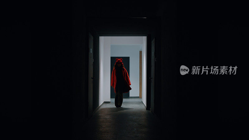 被照亮的红衣女人的剪影走在走廊上