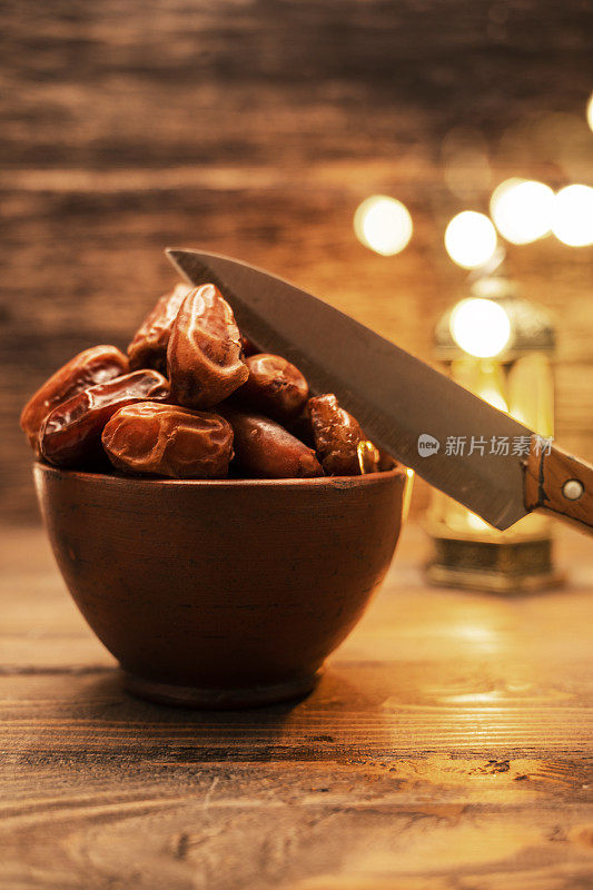 可口的干枣，水果和刀与阿拉伯光背景的形象。斋月穆斯林斋月的节日。