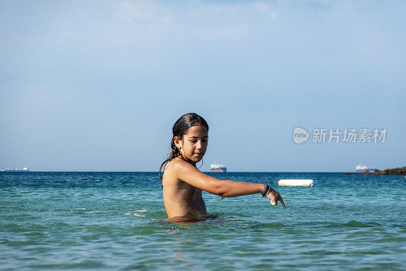 他用手在海里泼水。一个夏天的早晨。忒涅多斯岛。爱琴海北部，12岁的帅哥。长头发的