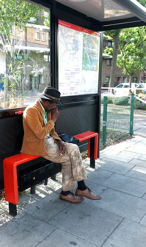 一个黑人老人坐在公共汽车站