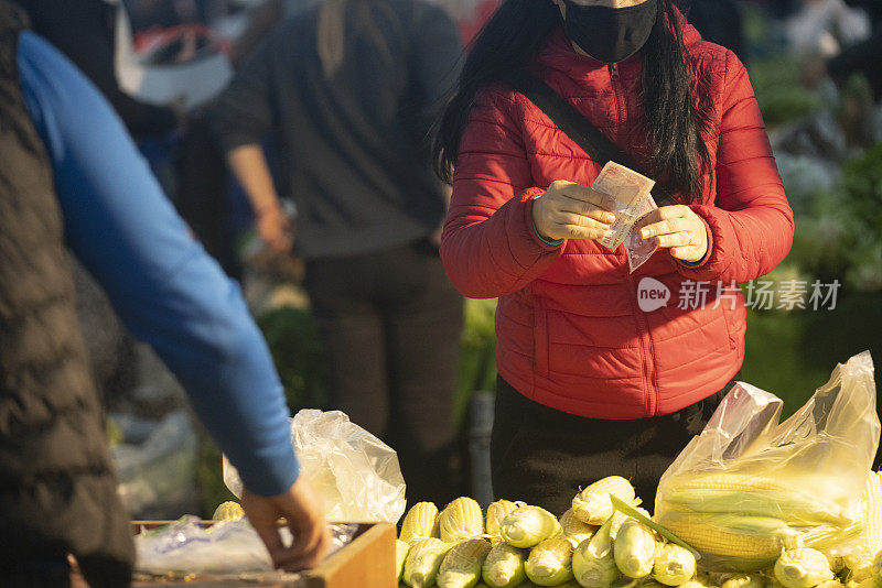 戴着防护口罩的妇女在农贸市场购物