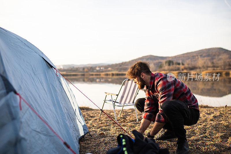 一个喜欢户外活动的年轻人在湖边搭起了帐篷