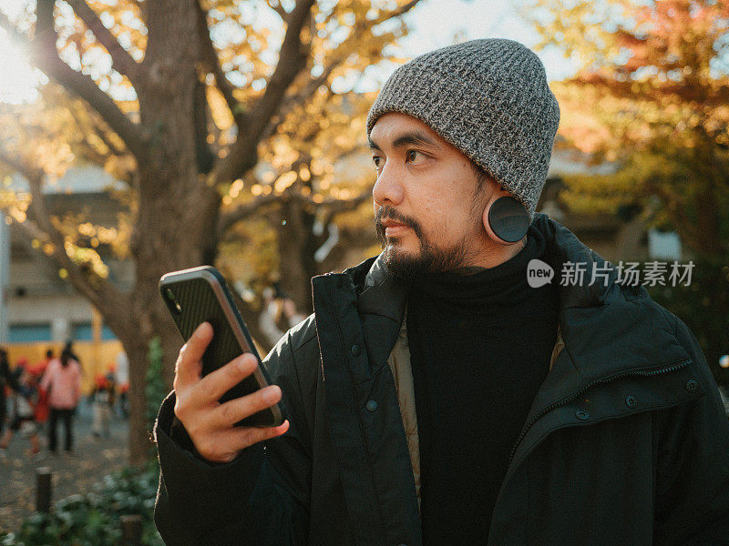 留着胡子的亚洲男人拿着智能手机。