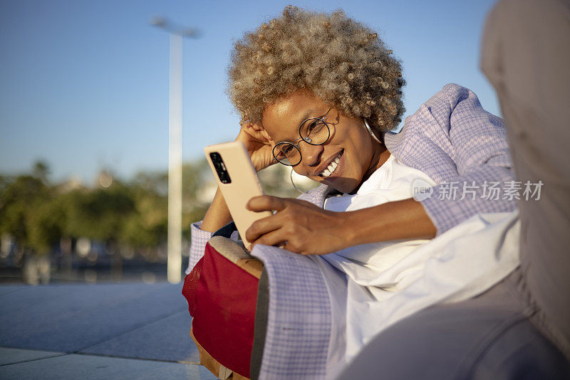 年轻的西班牙裔黑人女性在户外使用智能手机