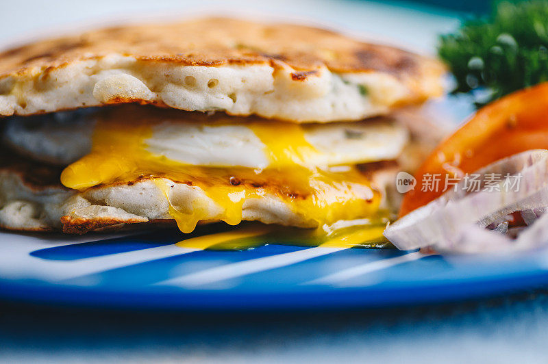 美味的煎蛋早餐三明治与切达干酪欧芹煎饼
