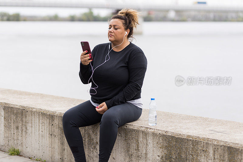 肥胖的西班牙裔妇女在移动应用程序上查看她的锻炼结果