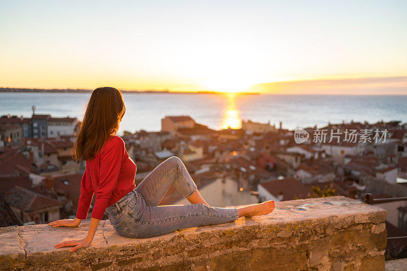 一名年轻女子在沿海村庄观看日出