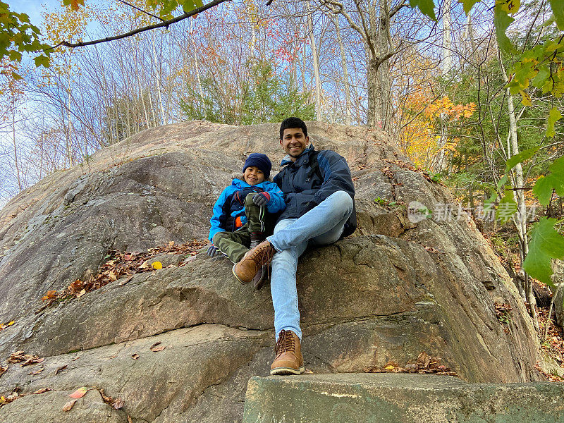 秋天，父子俩坐在一块大石头上