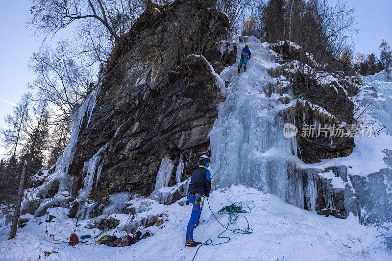 攀冰者在攀爬冰冻瀑布时保护其他攀冰者