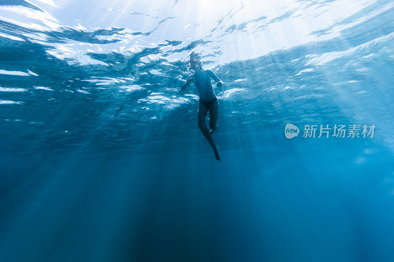 少女漂浮在热带清澈的蓝色海水之间的阳光