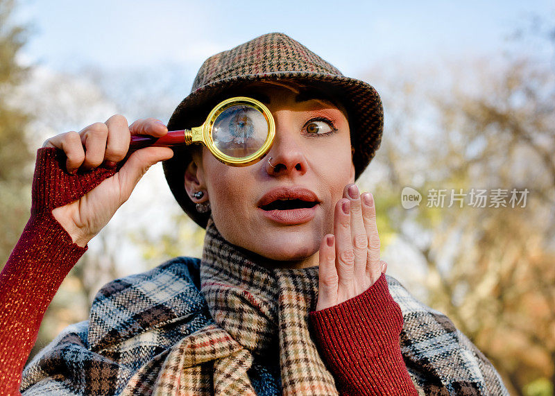 一个古怪的女人打扮成夏洛克·福尔摩斯，拿着老式相机在秋天的公园里寻找证据