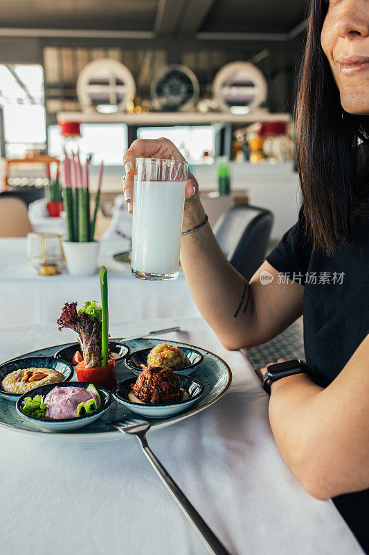 美丽的女人拿着土耳其拉基，在晚餐上吃美味的开胃菜