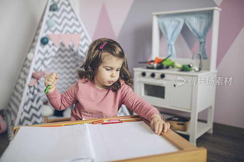 小女孩在她粉红色的房间里用蜡笔画画