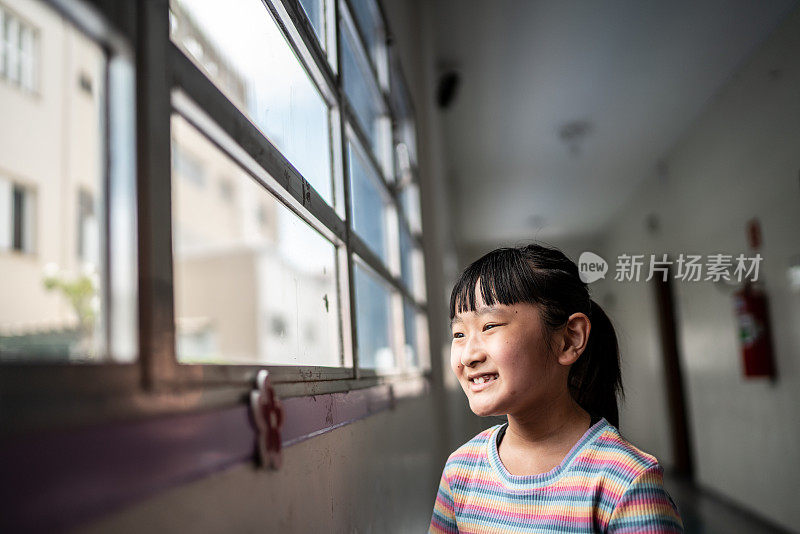 一个沉思的女孩从学校的窗户望出去