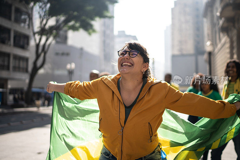 年轻女子举着巴西国旗在户外庆祝