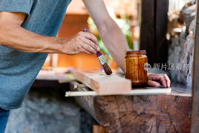 在阳光明媚的日子里，男人正在为家里的露台粉刷木板