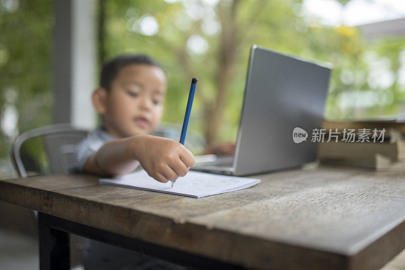 男孩正在学习用铅笔写字