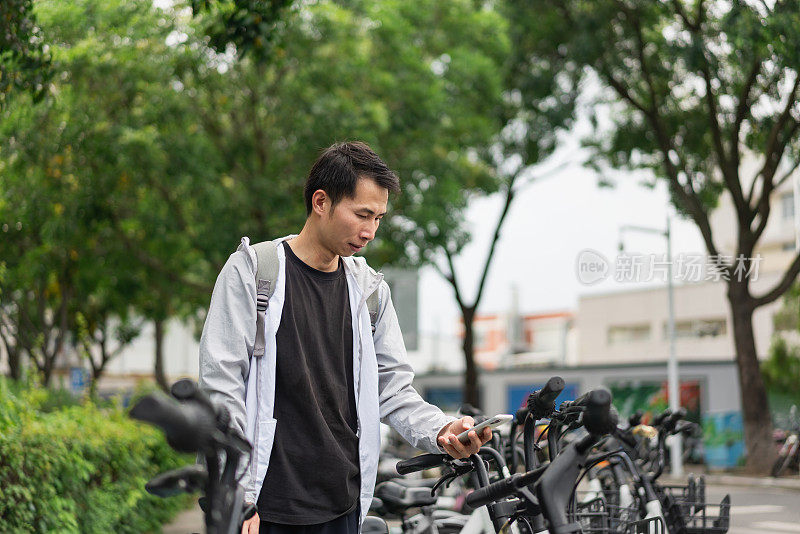 一名男子正在用手机扫描支付共享单车费用