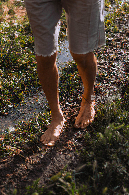 一个人光着脚走在泥泞的地上的垂直镜头