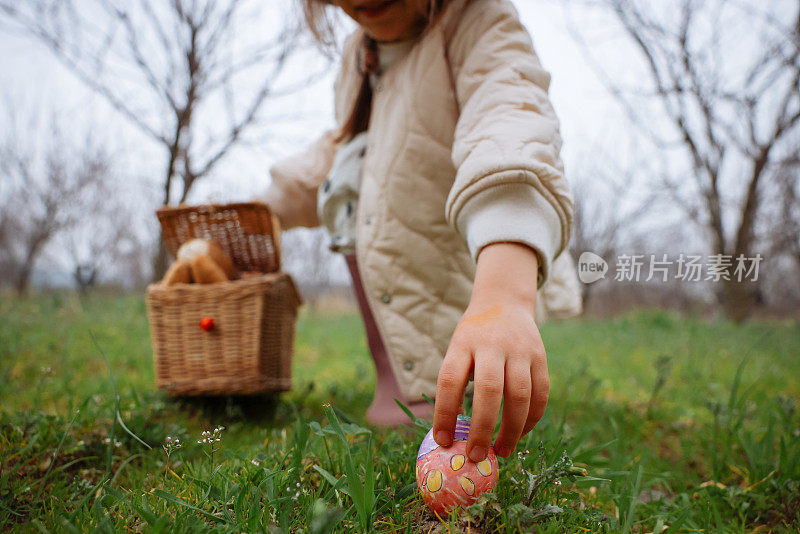 小女孩手里拿着五颜六色的复活节彩蛋。孩子们在春天公园里收集彩绘彩蛋。孩子们在户外寻找鸡蛋。