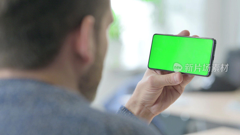 男子手持水平智能手机色度键绿色屏幕