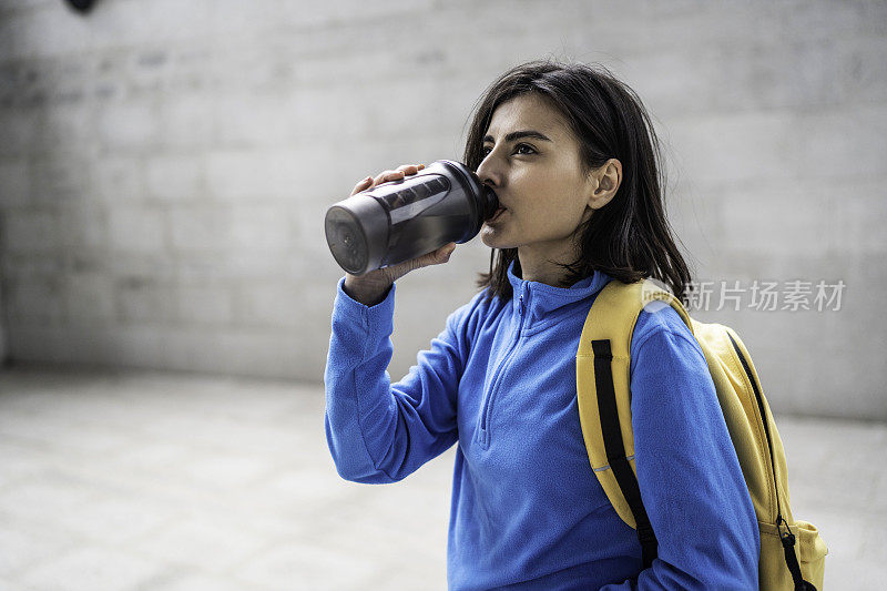 年轻女子在户外运动后喝水