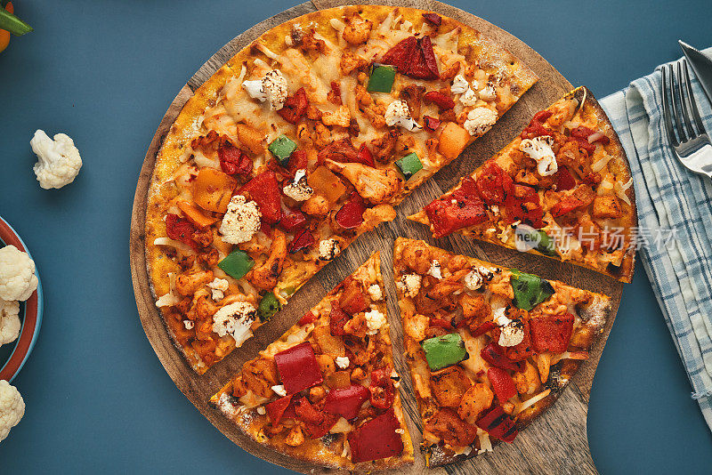 素食披萨配花椰菜姜黄底，顶部配烤甜椒，花椰菜和素食奶酪