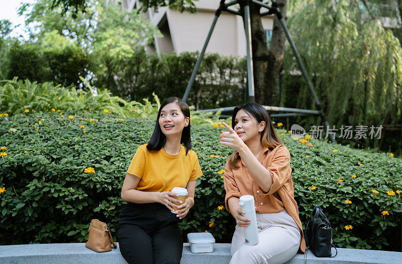 两个亚洲女人在城市花园闲逛聊天。