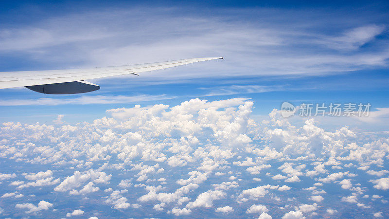 空中旅行，窗外望着飞机翅膀上的蓝天白云。