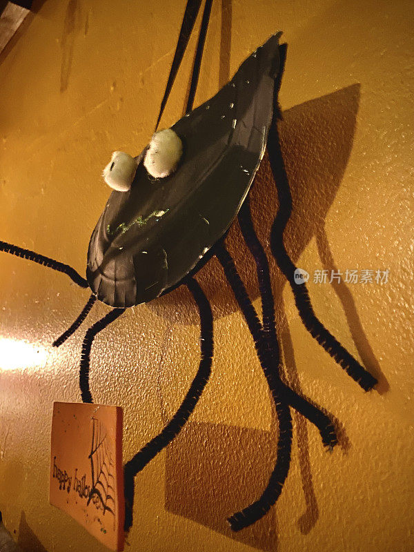 自制纸盘蜘蛛万圣节装饰挂在室内。