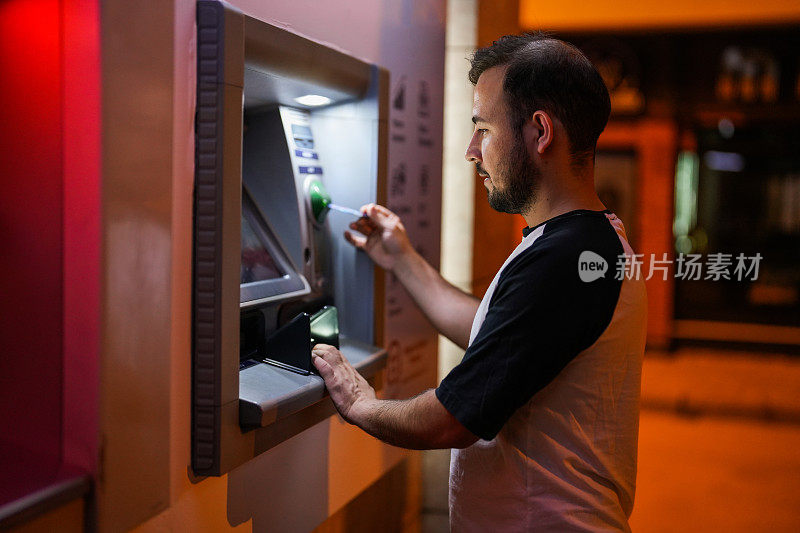 一名男子在晚上插入他的银行ATM卡取钱