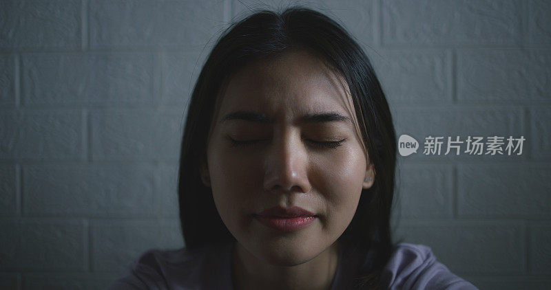 悲伤沮丧的年轻亚洲女子独自坐在家里的地板上哭泣