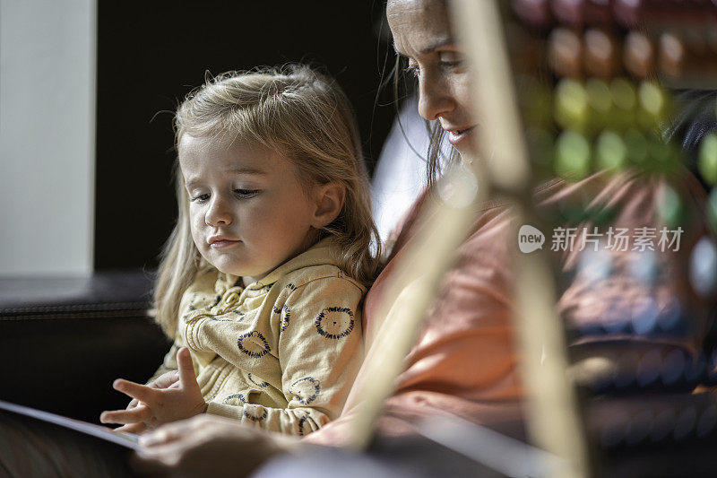 妈妈在家给她的孩子读书。家庭时间。