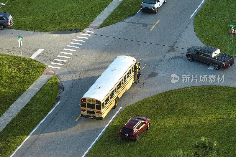 鸟瞰图清晨，美国黄色校车在人行道公交站接送孩子们上课。美国的公共交通