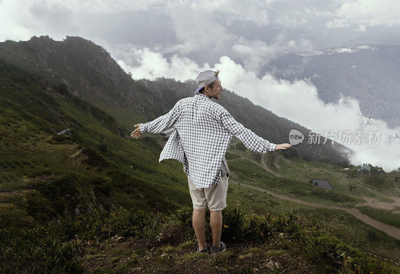 一个孤独的徒步旅行者穿过崎岖的山路，头顶上阴沉沉的天空突出了黄昏时大自然的宁静孤独。