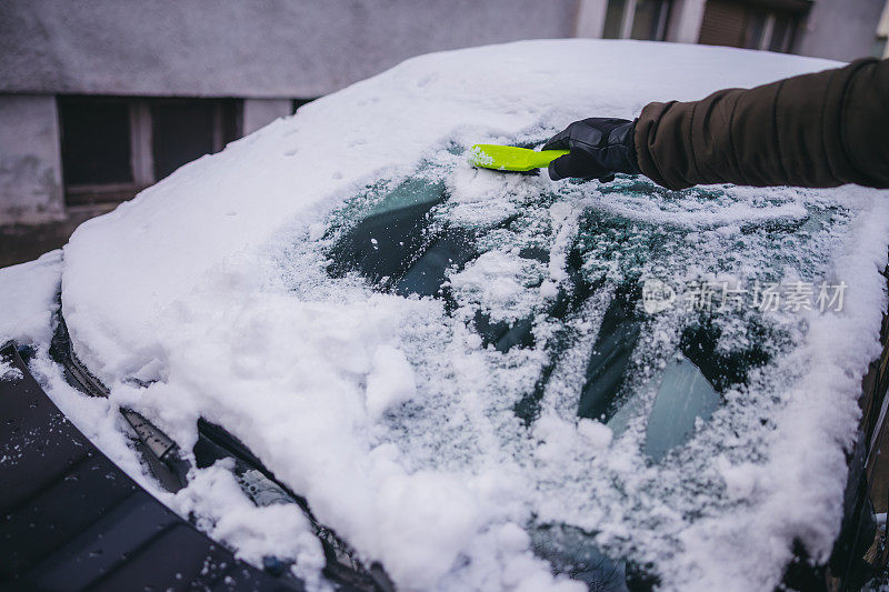 年轻人正在清除汽车上的积雪