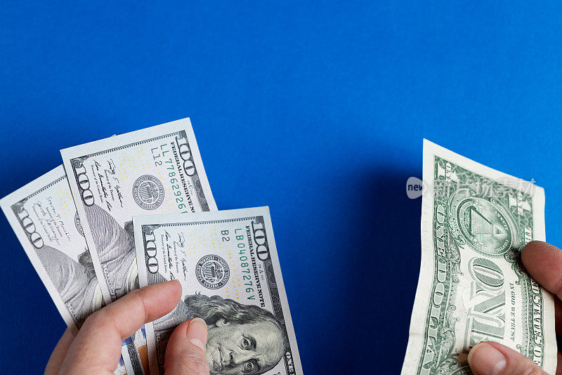女人的左手有三百美元的钞票，右手有一美元。蓝色背景。