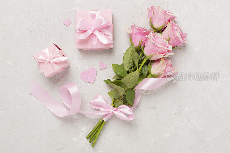 粉红色玫瑰与心和礼盒在混凝土背景，俯视图。情人节概念