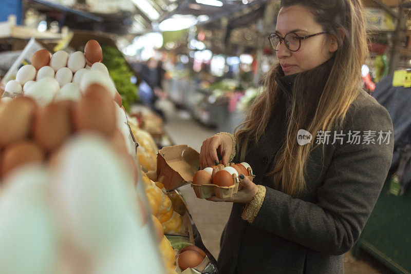 开朗的女人挑选鸡蛋，并把它们放在鸡蛋纸盒里