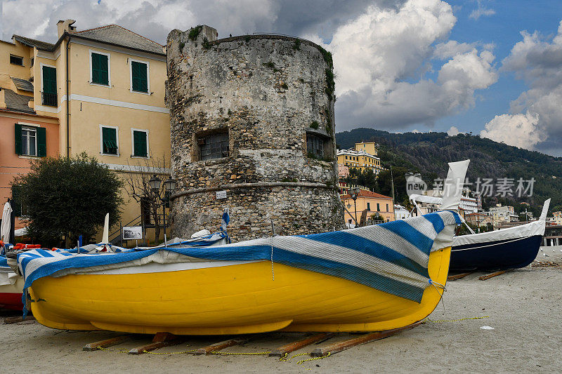 意大利里维埃拉度假胜地沙滩上的渔船，还有建于16世纪抵御海盗袭击的防御塔Baluardo，意大利利古里亚萨沃纳Laigueglia