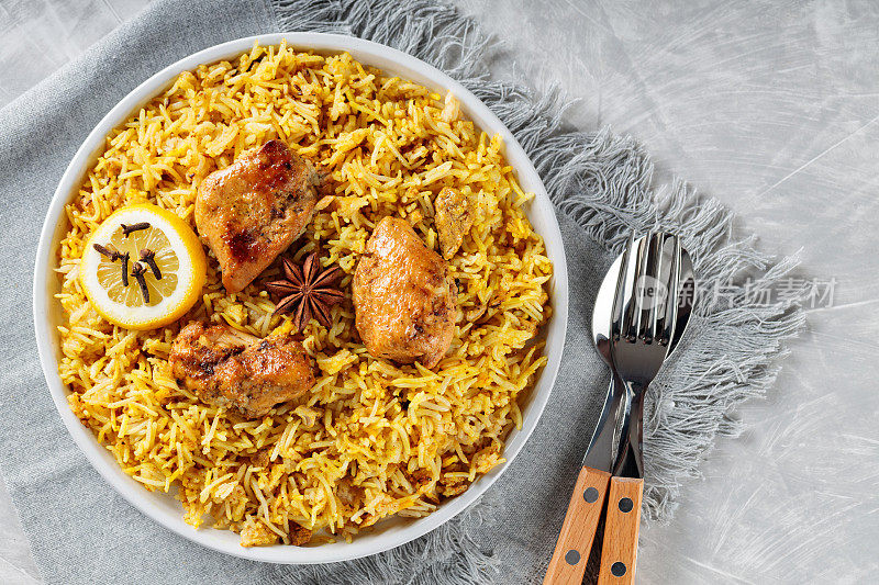 正宗的鸡肉印度香饭与香料和柠檬在白色盘子，传统的非素食的印度食物